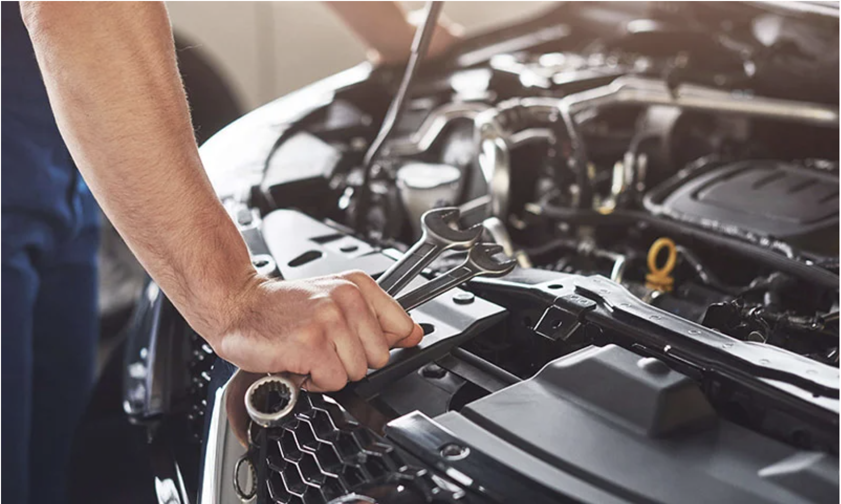 Detalle de mantenimiento automotriz con herramienta manual sobre el vano motor.