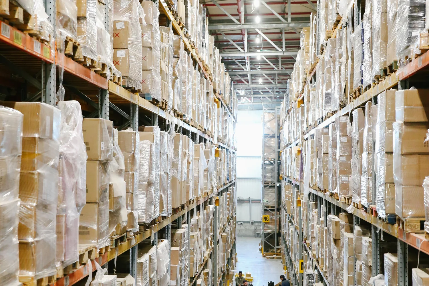 Mercancía en cajas y estanterías organizadas en un entorno logístico limpio.