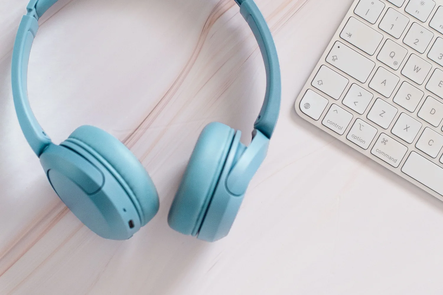 Escritorio tecnológico con auriculares, teclado y accesorios en una composición limpia.